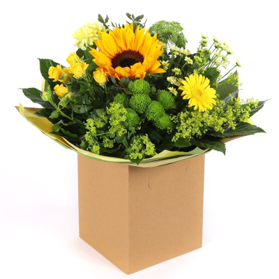 Golden Glow - Brighten someone's day with the `Golden Glow` arrangement, featuring a stunning sunflower mix with seasonal blooms. Complemented by lush green foliage, this arrangement brings a touch of nature's radiant beauty into any space.